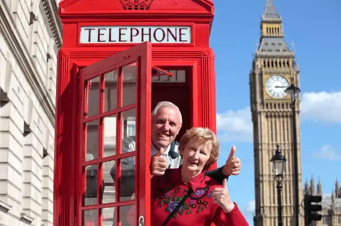 Older couple enjoying London sightseeing with Big Ben and red phone booth in the background